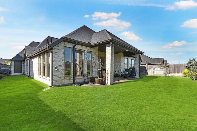 back of property featuring a patio, brick siding, fence, and a lawn