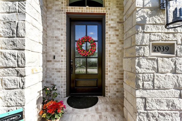 view of exterior entry with stone siding and brick siding