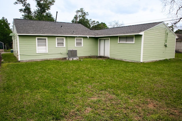 rear view of house with roof with shingles, a yard, and central air condition unit