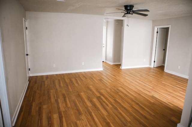empty room featuring baseboards, wood finished floors, and a ceiling fan