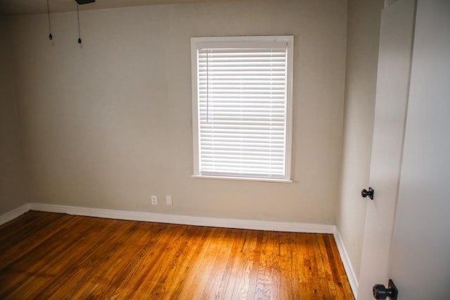 spare room featuring wood-type flooring and baseboards