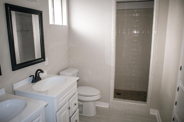 bathroom with a stall shower, toilet, two vanities, and a sink