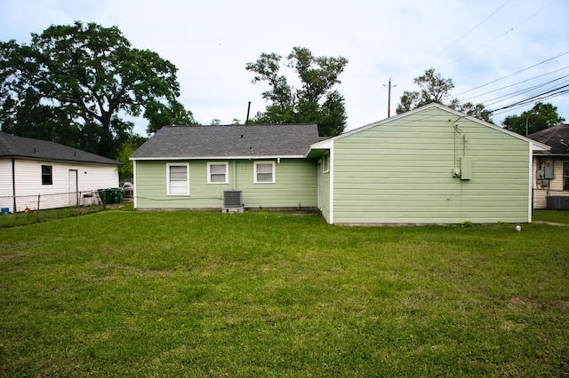 rear view of property featuring cooling unit, a yard, and fence