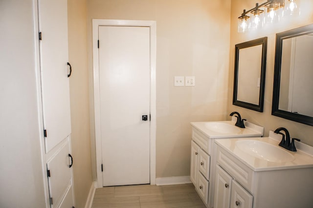 bathroom with baseboards, double vanity, and a sink
