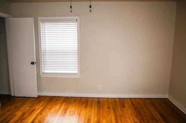 spare room with baseboards and wood-type flooring