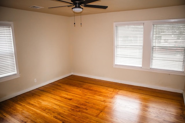 empty room featuring baseboards, visible vents, wood finished floors, and a ceiling fan