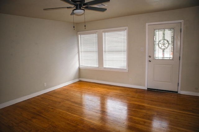 foyer entrance featuring wood finished floors, ceiling fan, visible vents, and baseboards