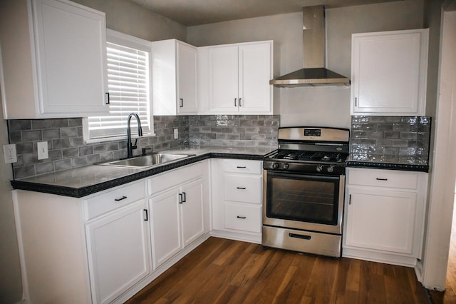 kitchen featuring wall chimney range hood, a sink, dark countertops, dark wood-style floors, and gas stove