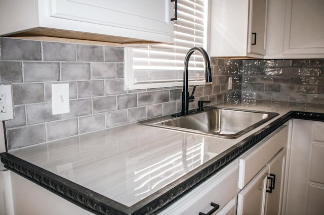 kitchen with white cabinetry, decorative backsplash, and a sink