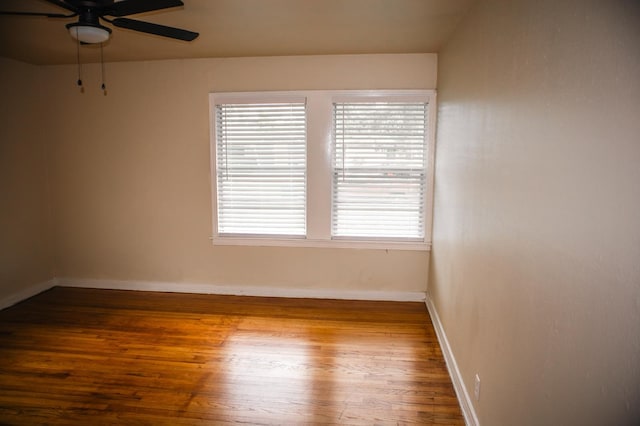 empty room with ceiling fan, a healthy amount of sunlight, hardwood / wood-style flooring, and baseboards