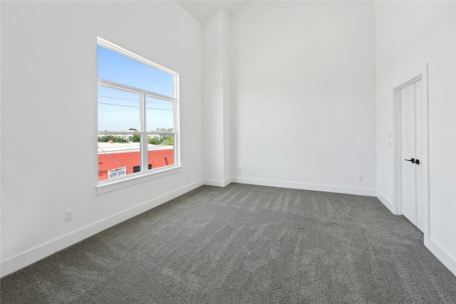 spare room with dark colored carpet and baseboards