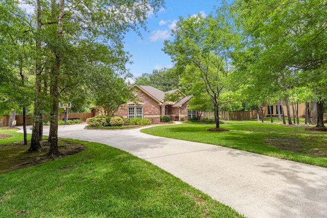 view of home's community with fence, curved driveway, and a lawn