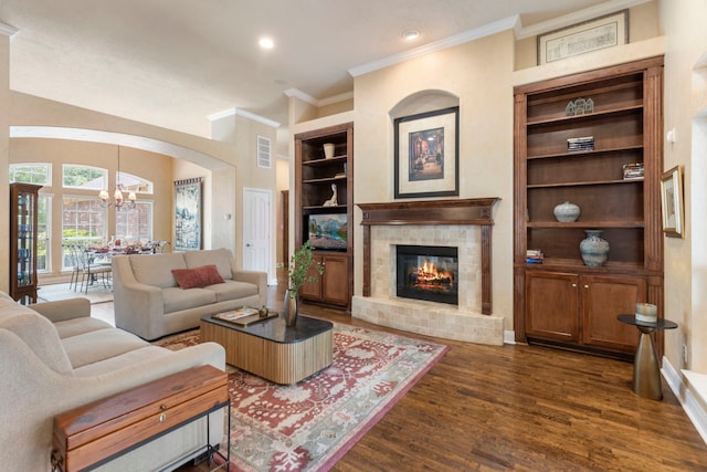 living room featuring visible vents, built in shelves, an inviting chandelier, ornamental molding, and dark wood-type flooring