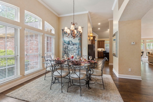 dining space featuring a towering ceiling, crown molding, baseboards, a chandelier, and dark wood-type flooring