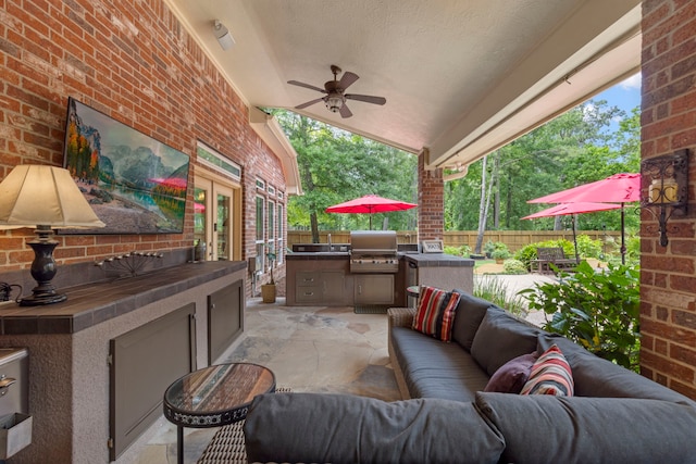view of patio featuring area for grilling, ceiling fan, exterior kitchen, fence, and an outdoor hangout area