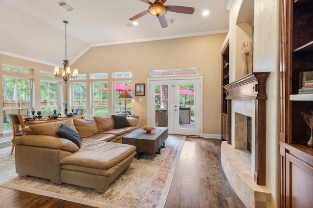 living area featuring plenty of natural light, ceiling fan with notable chandelier, wood finished floors, and visible vents
