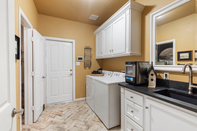 washroom featuring a textured ceiling, brick floor, washing machine and clothes dryer, a sink, and cabinet space