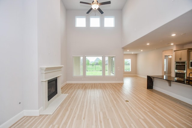 6939 Shoreline View Dr, Katy, TX 77493 - unfurnished living room featuring ceiling fan, a glass covered fireplace, plenty of natural light, and baseboards
