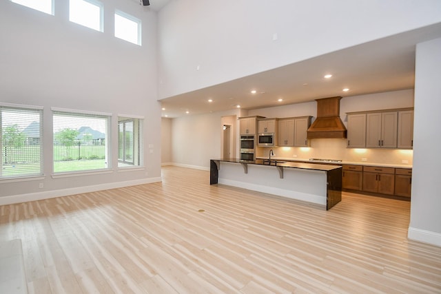 6939 Shoreline View Dr, Katy, TX 77493 - kitchen with open floor plan, a kitchen breakfast bar, premium range hood, a sink, and stainless steel appliances