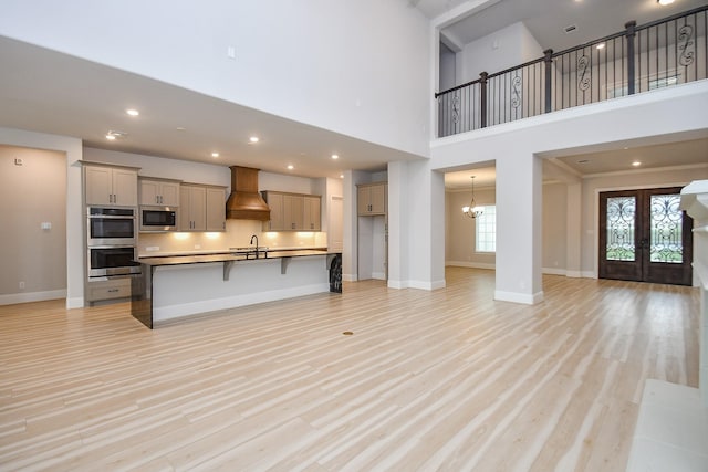 6939 Shoreline View Dr, Katy, TX 77493 - unfurnished living room featuring a sink, baseboards, french doors, and light wood-type flooring
