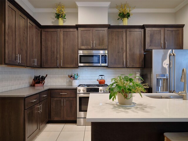 kitchen featuring light countertops, stainless steel appliances, dark brown cabinetry, and light tile patterned floors