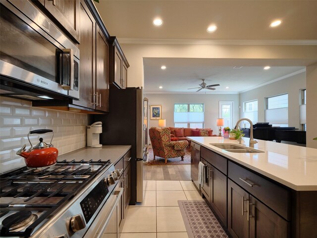 kitchen with dark brown cabinets, open floor plan, appliances with stainless steel finishes, and a sink