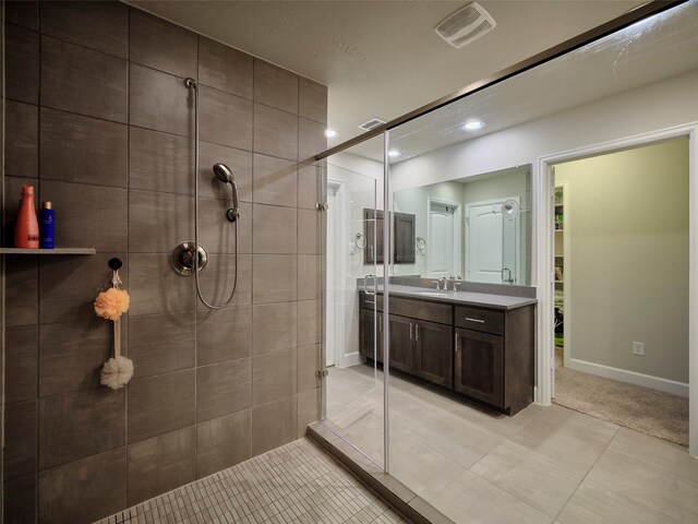 bathroom with visible vents, a tile shower, vanity, baseboards, and recessed lighting
