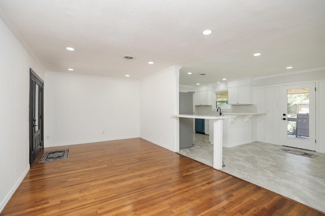 5714 Nina Lee Ln, Houston, TX 77092 - unfurnished living room with light wood-type flooring, crown molding, recessed lighting, a sink, and baseboards