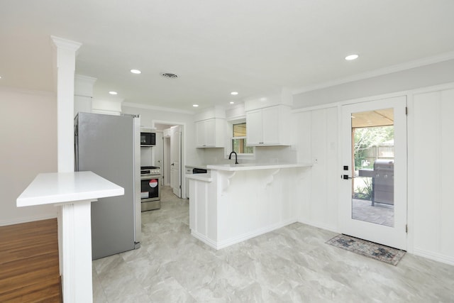 5714 Nina Lee Ln, Houston, TX 77092 - kitchen with appliances with stainless steel finishes, a peninsula, a kitchen breakfast bar, light countertops, and ornamental molding