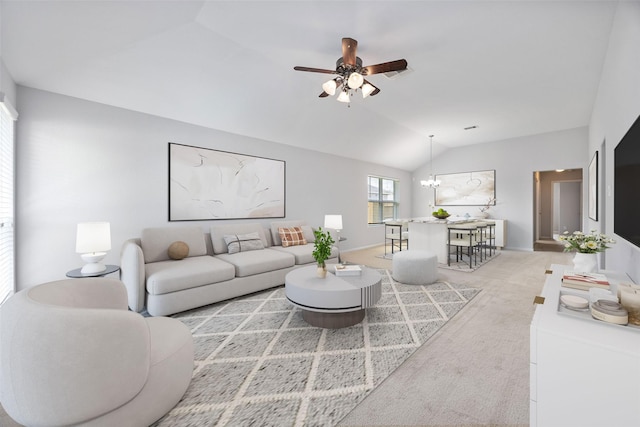 living area with vaulted ceiling, light colored carpet, and ceiling fan with notable chandelier