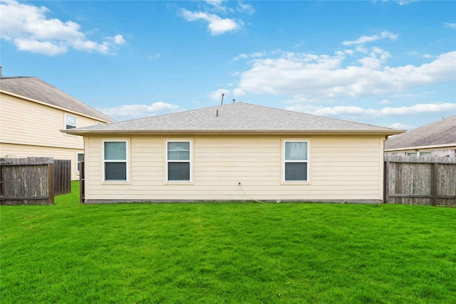 rear view of property with a fenced backyard and a yard