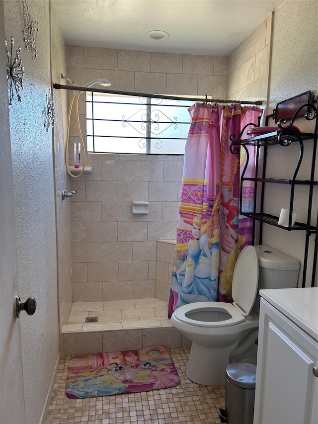 full bathroom with vanity, a textured wall, toilet, tiled shower, and tile patterned floors