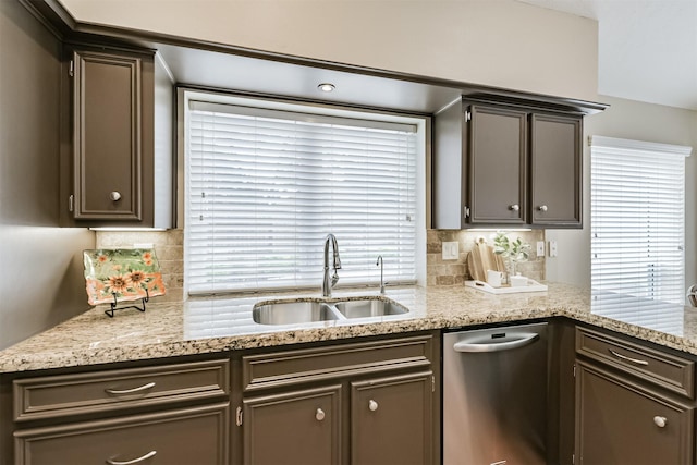 kitchen featuring a sink, light stone counters, decorative backsplash, and stainless steel dishwasher