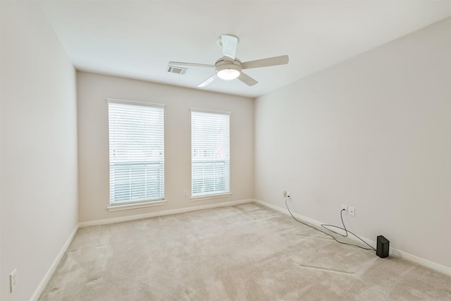 empty room featuring a ceiling fan, baseboards, light colored carpet, and visible vents