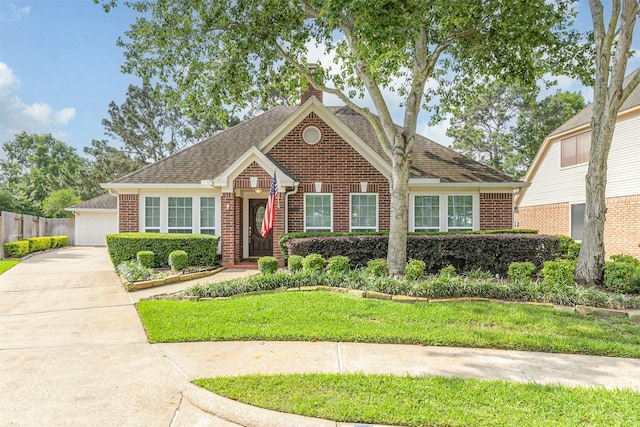 view of front of home with a shingled roof, brick siding, a garage, a front yard, and a chimney