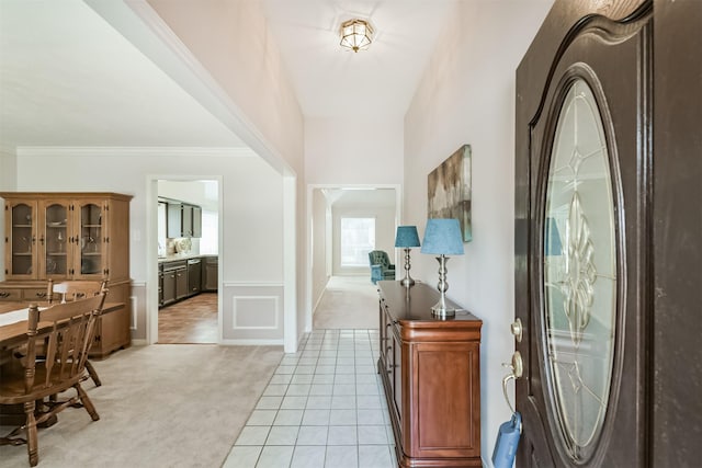 foyer entrance featuring ornamental molding, light carpet, and light tile patterned floors