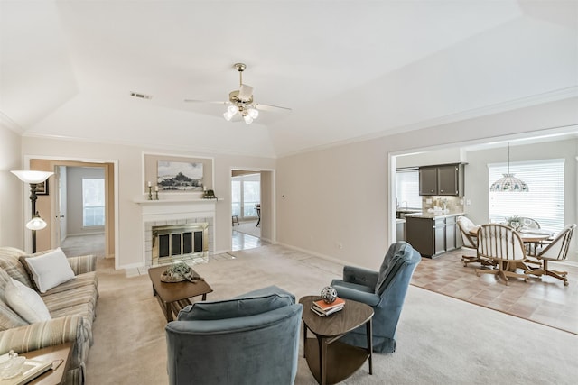 living area featuring light colored carpet, a ceiling fan, baseboards, a tile fireplace, and visible vents
