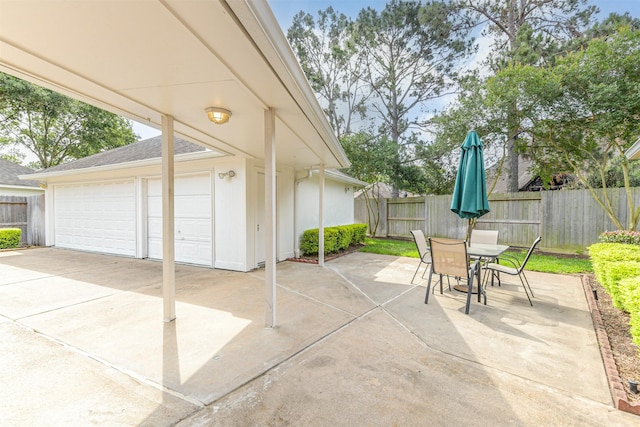 view of patio featuring a fenced backyard, an outbuilding, outdoor dining area, and a garage