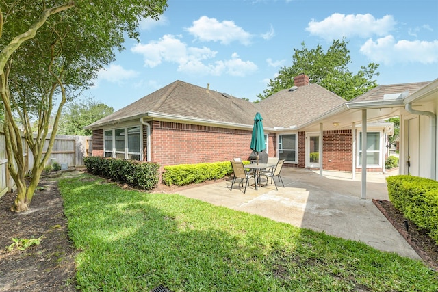 back of property featuring a chimney, roof with shingles, brick siding, fence, and a patio