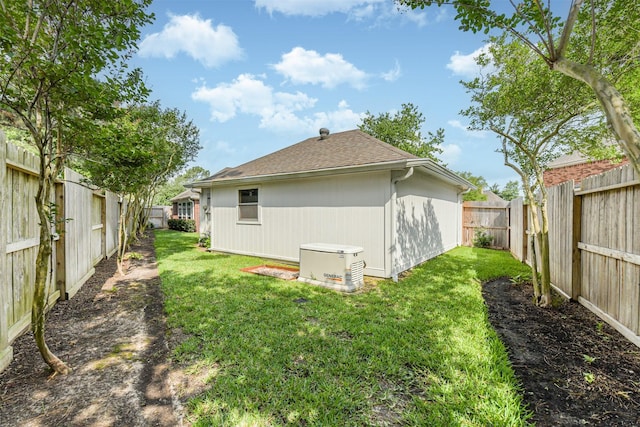 rear view of property with a yard, a shingled roof, and a fenced backyard
