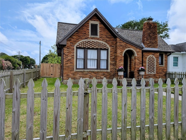 view of front facade featuring roof with shingles, a fenced front yard, a chimney, and brick siding