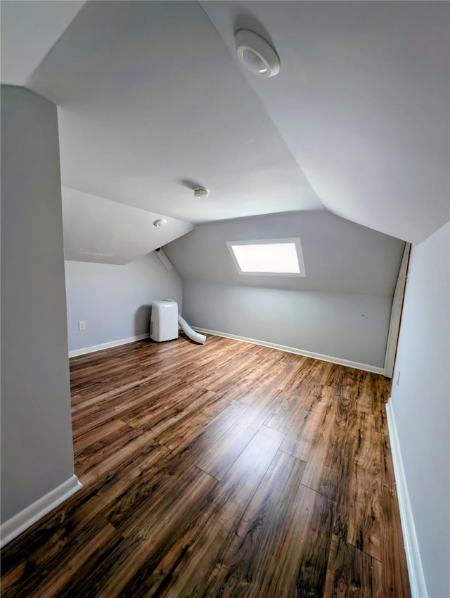 bonus room featuring baseboards, wood finished floors, and lofted ceiling with skylight