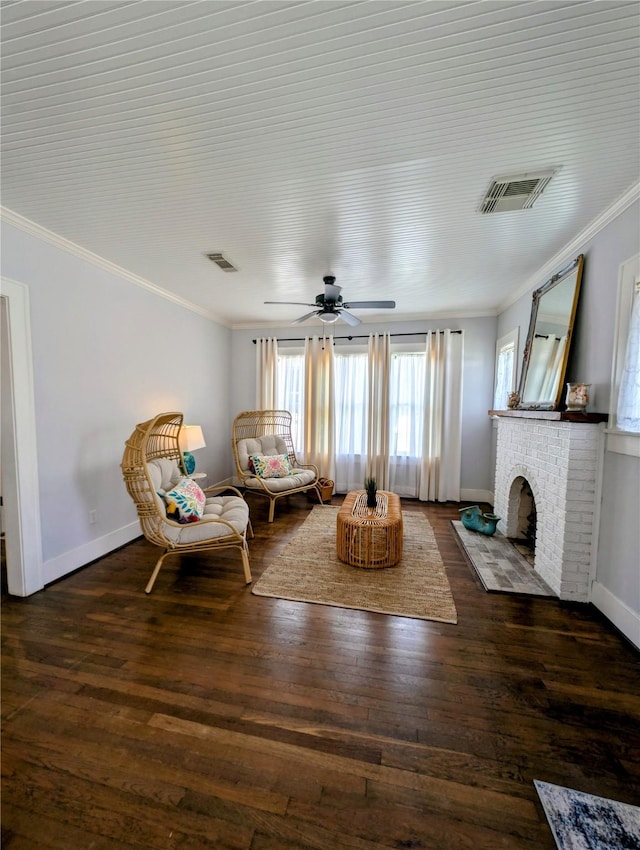 living area with visible vents, crown molding, wood finished floors, and a fireplace