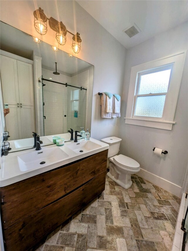 bathroom with double vanity, visible vents, a shower stall, a sink, and baseboards