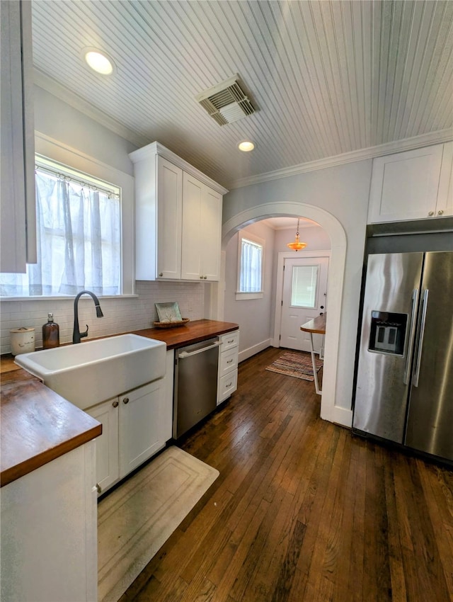 kitchen with wooden counters, visible vents, appliances with stainless steel finishes, arched walkways, and a sink