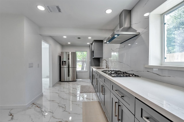 kitchen featuring gas cooktop, exhaust hood, gray cabinets, visible vents, and stainless steel fridge
