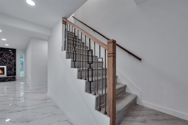 stairway with recessed lighting, marble finish floor, baseboards, and a fireplace