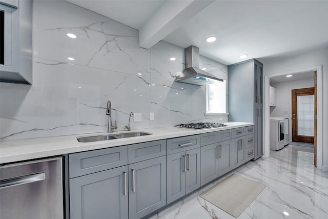 kitchen with appliances with stainless steel finishes, a sink, washer / clothes dryer, island exhaust hood, and gray cabinetry