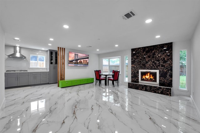 living room featuring a high end fireplace, marble finish floor, recessed lighting, and visible vents