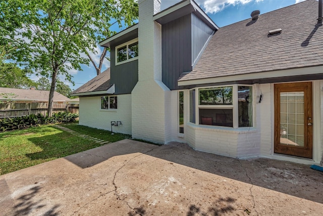 back of property featuring brick siding, fence, a chimney, and a patio